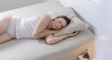 Beautiful woman in pajamas lying on her side in her bed.