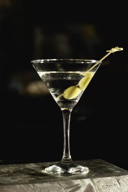 Arkaplanda yeşil zeytinli sek sek martini iç..