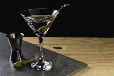 Arkaplanda yeşil zeytinli sek sek martini iç..