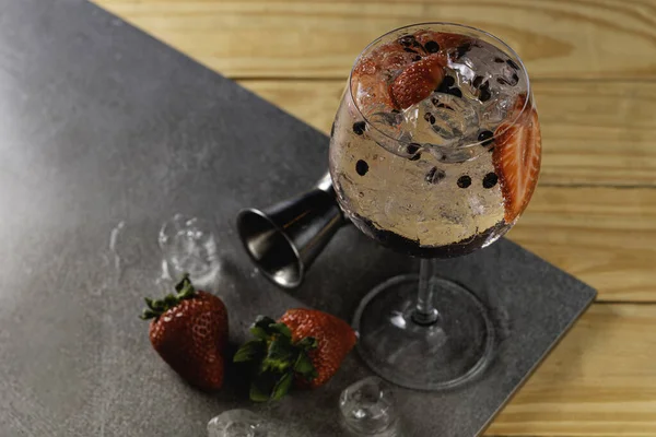 Gin tonic strawberry with juniper stone background in gray color.