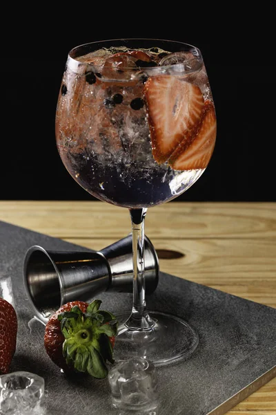 Gin tonic strawberry with juniper stone background in gray color.