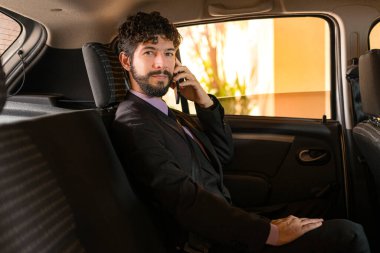 İş adamı başvuru arabasında telefonla konuşuyor..