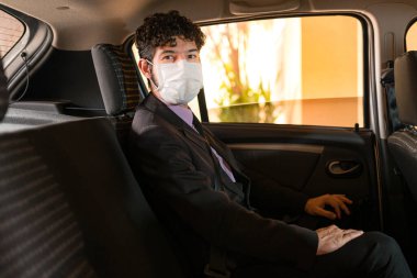 İş adamı araç servisinde koruyucu maske kullanıyor.