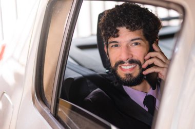 Araba servisindeki yakışıklı Latin iş adamı cep telefonuyla konuşuyor..