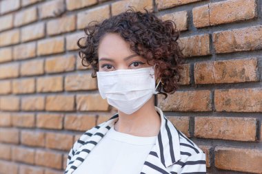Sokakta koruyucu maske takan genç bir kadının portresi.