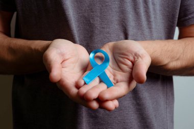 Açık mavi kurdele tutan adam. Farkındalık kurdelesi.
