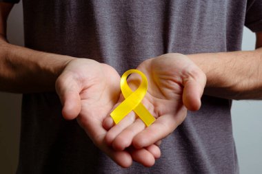 Man holding yellow ribbon. Awareness ribbon. clipart
