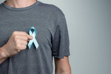 Adam gömleğine cyan bandı yapıştırıyor. Bilinç sembolü.