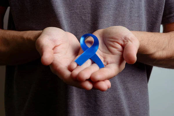 Man holding dark blue ribbon. Awareness ribbon.