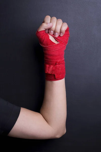 Female arm bandaged red boxing tape is raised upwards as a symbol of the struggle for rights. Fight like a girl