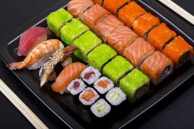 Japon Suşi bir çizgi şeklinde siyah plaka arka plan üstten görünüm üzerinde rulo.