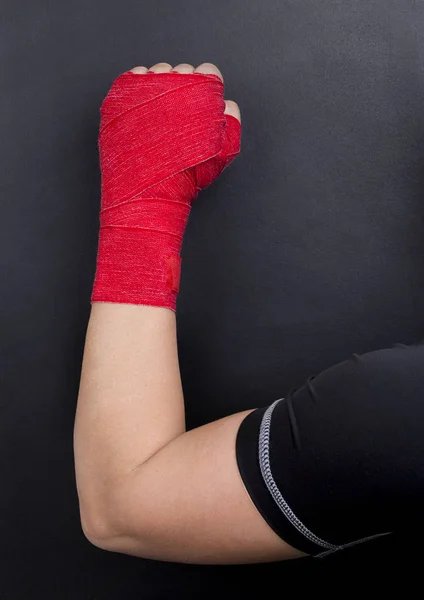 Female hand in a bandage with red boxing tape is raised upwards as a symbol of the struggle for rights. Fight like a girl