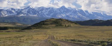 Panorama bir dağ yolda yeşil tepeler ve yüksek karlı dağlar