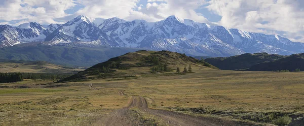 Panorama bir dağ yolda yeşil tepeler ve yüksek karlı dağlar