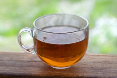 Saydam bir arka plan doğa üzerinde ahşap bir masa üzerinde siyah sıcak çay fincan