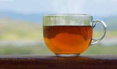 Saydam bir arka plan doğa üzerinde ahşap bir masa üzerinde siyah sıcak çay fincan