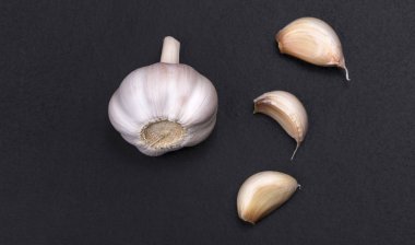 Bütün bir parçası ve bir siyah kara tahta arka plan üzerinde üstten görünüm izole pembe sarımsak dilimleri