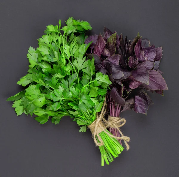 Two bunches of red basil and to a parsley bandaged with a rope with a bow isolated on a black background