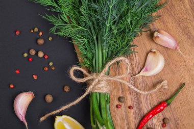Bir demet taze dereotu bir yay ve baharat ve sarımsak bir kara tahta, üstten görünüm üzerinde karışımı ile bir ip ile sargılı