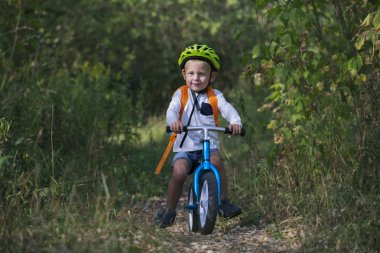 Bir denge Bisiklet küçük bir çocuk bir atlama yaz güneşli bir günde ormandaki bir yol üzerinde gerçekleştirir