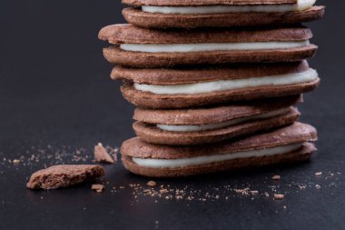 Yakın çekim yan görünüm, siyah bir arka plan doldurarak beyaz Kremalı çikolatalı sandviç kurabiye