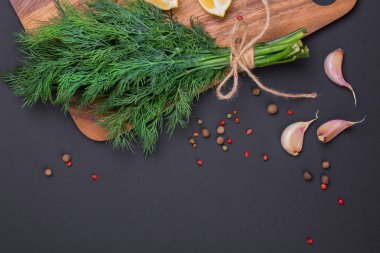 Bir demet taze dereotu bir yay ve baharat ve sarımsak bir kara tahta, üstten görünüm üzerinde karışımı ile bir ip ile sargılı