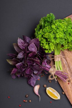 Bir avuç taze maydanoz ve kırmızı fesleğen fiyonk ve baharat ve sarımsak bir kara tahta, üstten görünüm üzerinde bir karışımı ile bir ip ile sargılı