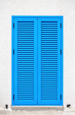 Santorini güneşli bir Yunan tarzında beyaz bir duvar üzerinde mavi panjurlar ile bir pencere.