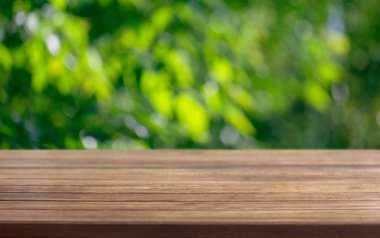 Bir sunum ahşap masa yüzeyi için arka plan şablonu ve bir yaz güneşli bir gün arka planda bir ağacın yaprakları bulanık