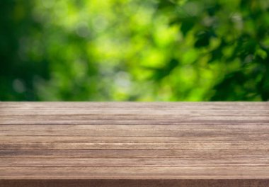 Bir sunum ahşap masa yüzeyi için arka plan şablonu ve bir yaz güneşli bir gün arka planda bir ağacın yaprakları bulanık