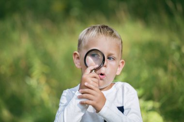 Genç araştırmacı büyüteç ile doğa araştırıyor 