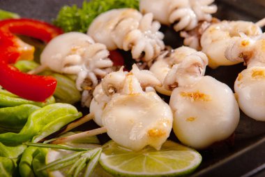 Ahşap bir şiş üzerinde bebek mürekkepbalığı ızgara