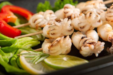 Ahşap bir şiş üzerinde bebek mürekkepbalığı ızgara