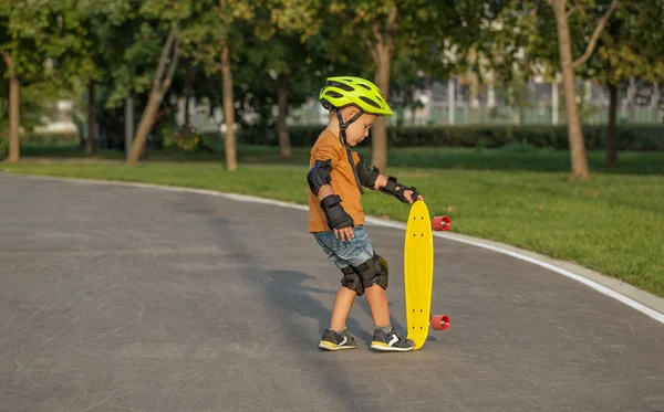 En lille dreng nyder en gul cruiser penny plastboard - Stock-foto