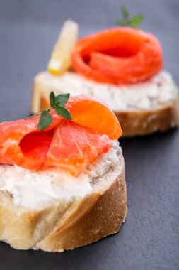 Siyah arka planda iki küçük somon sandviçi.