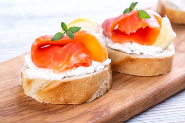 Beyaz ahşap bir masada mini somon sandviçi.