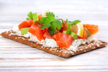 Tütsülenmiş somon sandviçi, diyet üzerine avokado, tahıl ekmeği, beyaz ahşap bir masada.