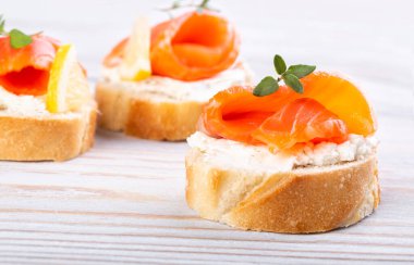 Beyaz ahşap bir masada mini somonlu sandviç.