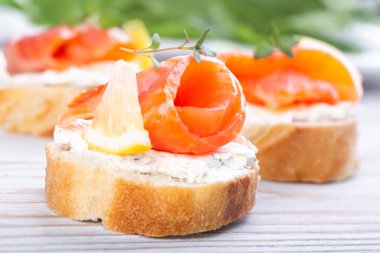 Beyaz ahşap bir masada mini somonlu sandviç.