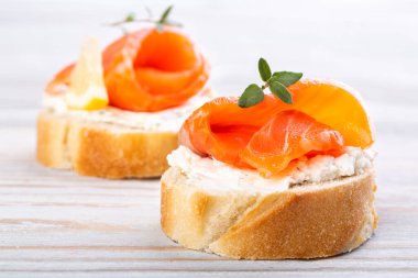 Beyaz ahşap bir masada mini somonlu sandviç.