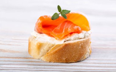 Beyaz ahşap bir masada mini somonlu sandviç.