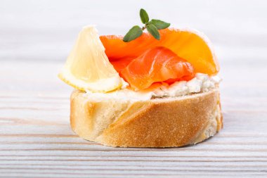 Beyaz ahşap bir masada mini somonlu sandviç.