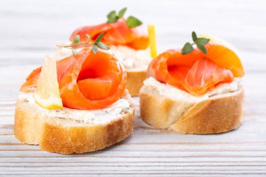 Beyaz ahşap bir masada mini somonlu sandviç.