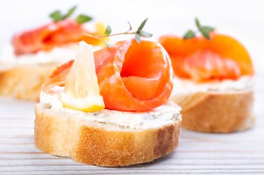 Beyaz ahşap bir masada mini somonlu sandviç.