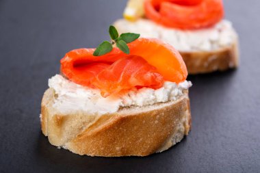 Siyah arka planda iki küçük somon sandviçi.