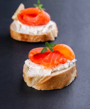 Siyah arka planda iki küçük somon sandviçi.