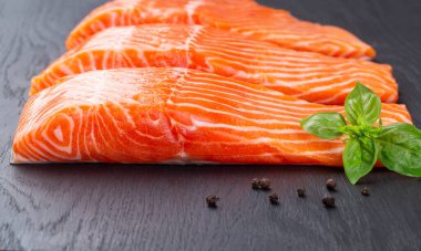 Siyah ahşap bir masada üç parça çiğ somon.