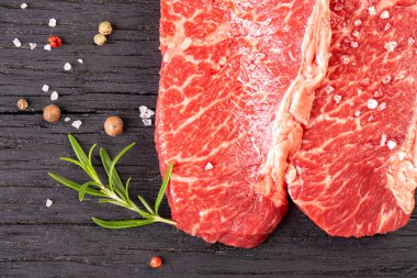 Ahşap arka planda iki taze mermer biftek.