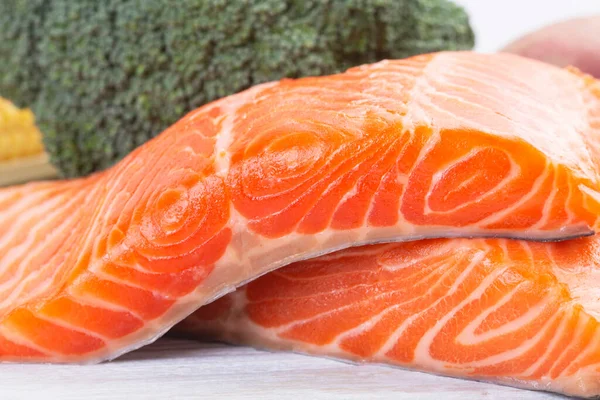 Fresh salmon and mix vegetables on a wooden white table