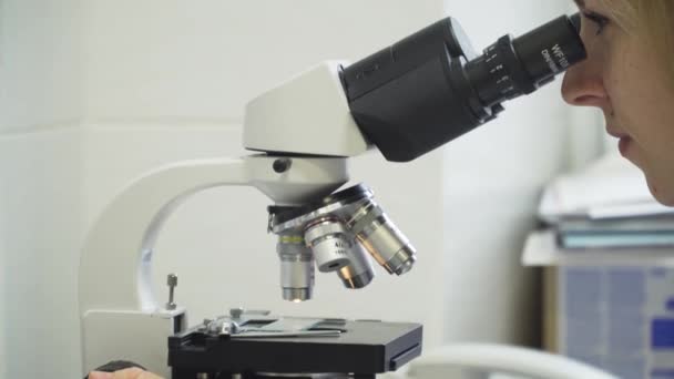 Mulher médico olha em um microscópio. — Vídeo de Stock